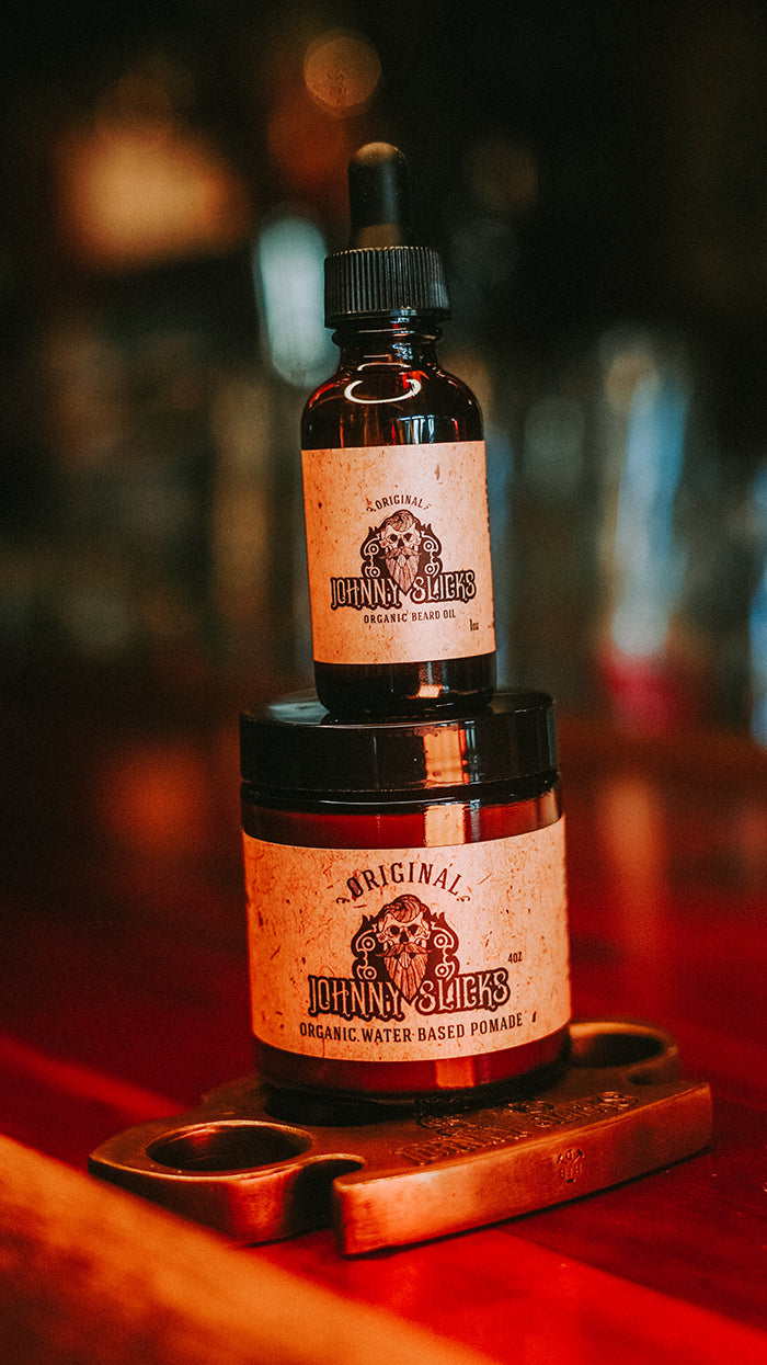 Amber beard oil bottle stacked with pomade jar, tan labels and black dropper caps