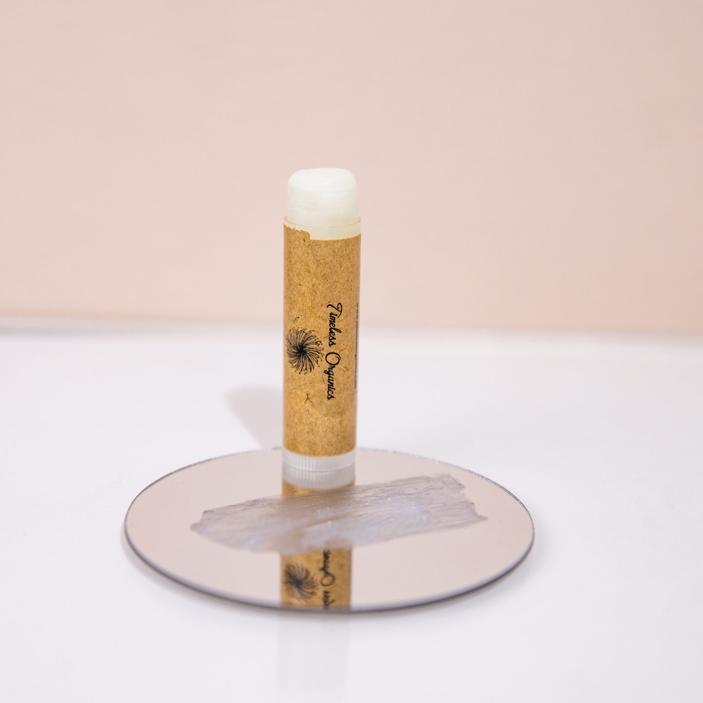 Lip balm tube with white cap and beige body, seen upright on a round base