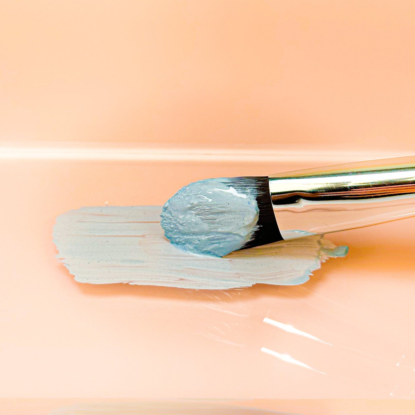 Blue clay face mask paste spread on skin with flat brush