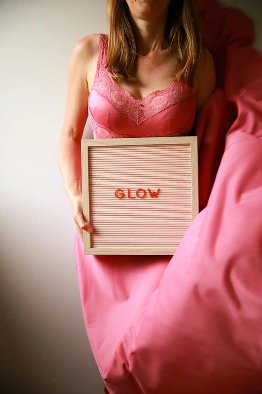 Woman in pink, holding a sign that says glow.