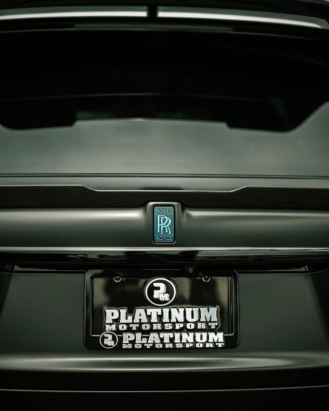 Close-up of a rolls-royce car's rear emblem and license plate.