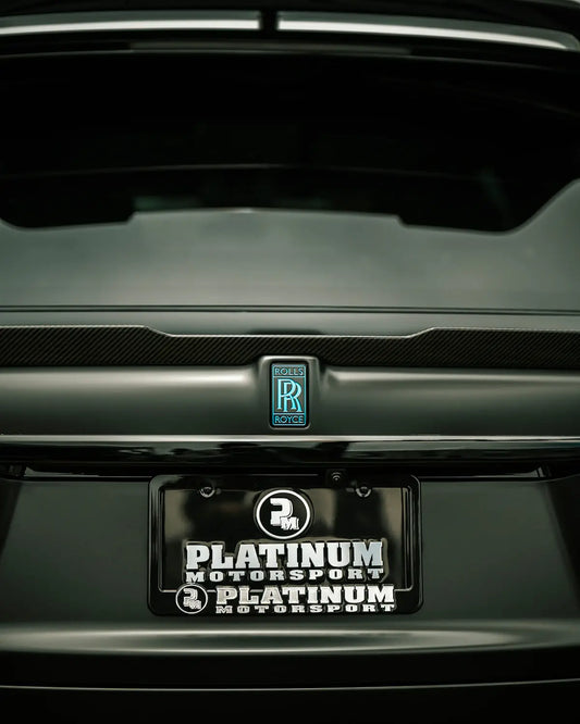 Close-up of a rolls-royce car's rear emblem and license plate.