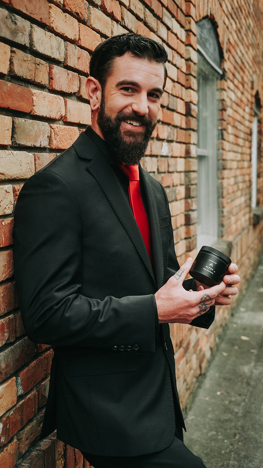 Small black pomade jar with Alpha label held in hand