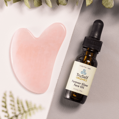 Anti-aging facial massage kit close-up of rose quartz gua sha and face oil bottle