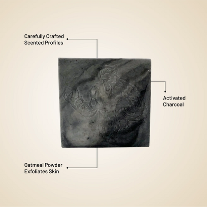 Square soap bar, dark charcoal color, with feature callouts (activated charcoal, oatmeal powder)