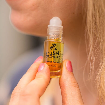 TruSelf ORGANICS blemish remedy spot treatment bottle held in hand, white cap.