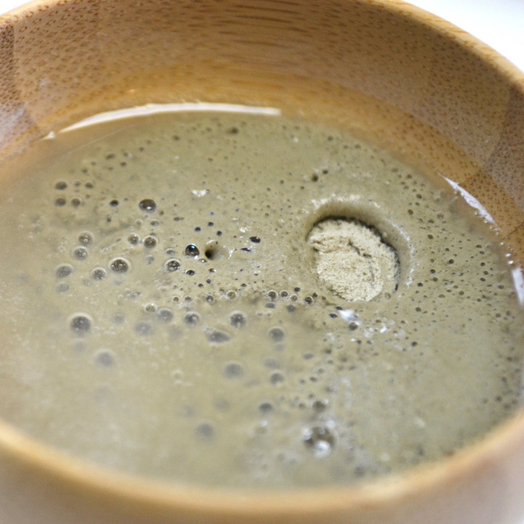 Detoxifying mask clay paste in bowl, pale green with small bubbles