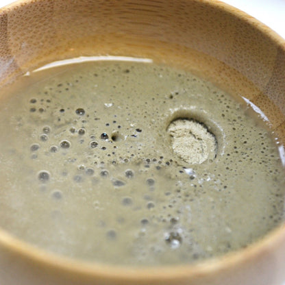 Detoxifying mask clay paste in bowl, pale green with small bubbles