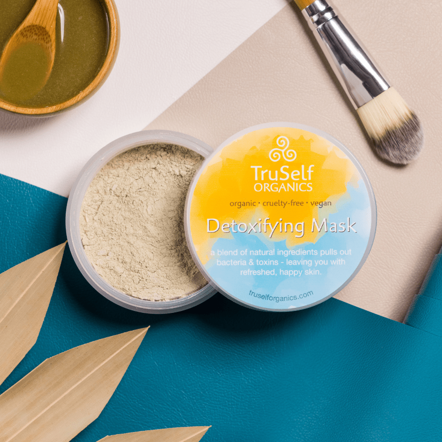 Detoxifying mask jar with pale powder inside and TruSelf Organics label; brush nearby