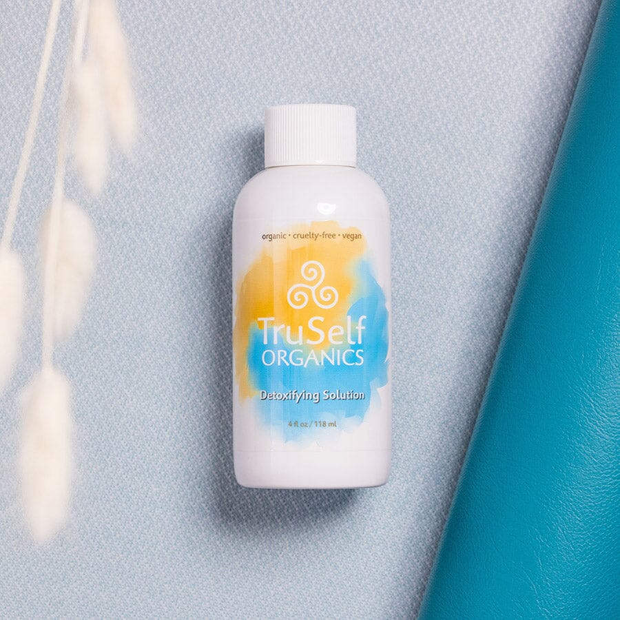Detoxifying solution bottle, white with orange-blue swirl label and ribbed cap