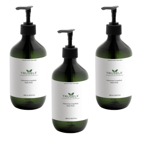Three body wash bottles with black pumps, white grapefruit labels, dark green glass