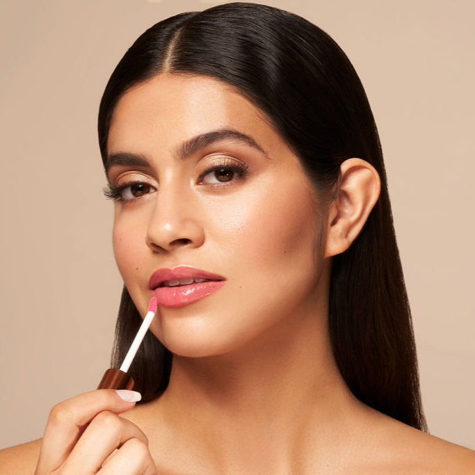 Glossy lip oil with pink tint applied to lips using a white doe-foot applicator