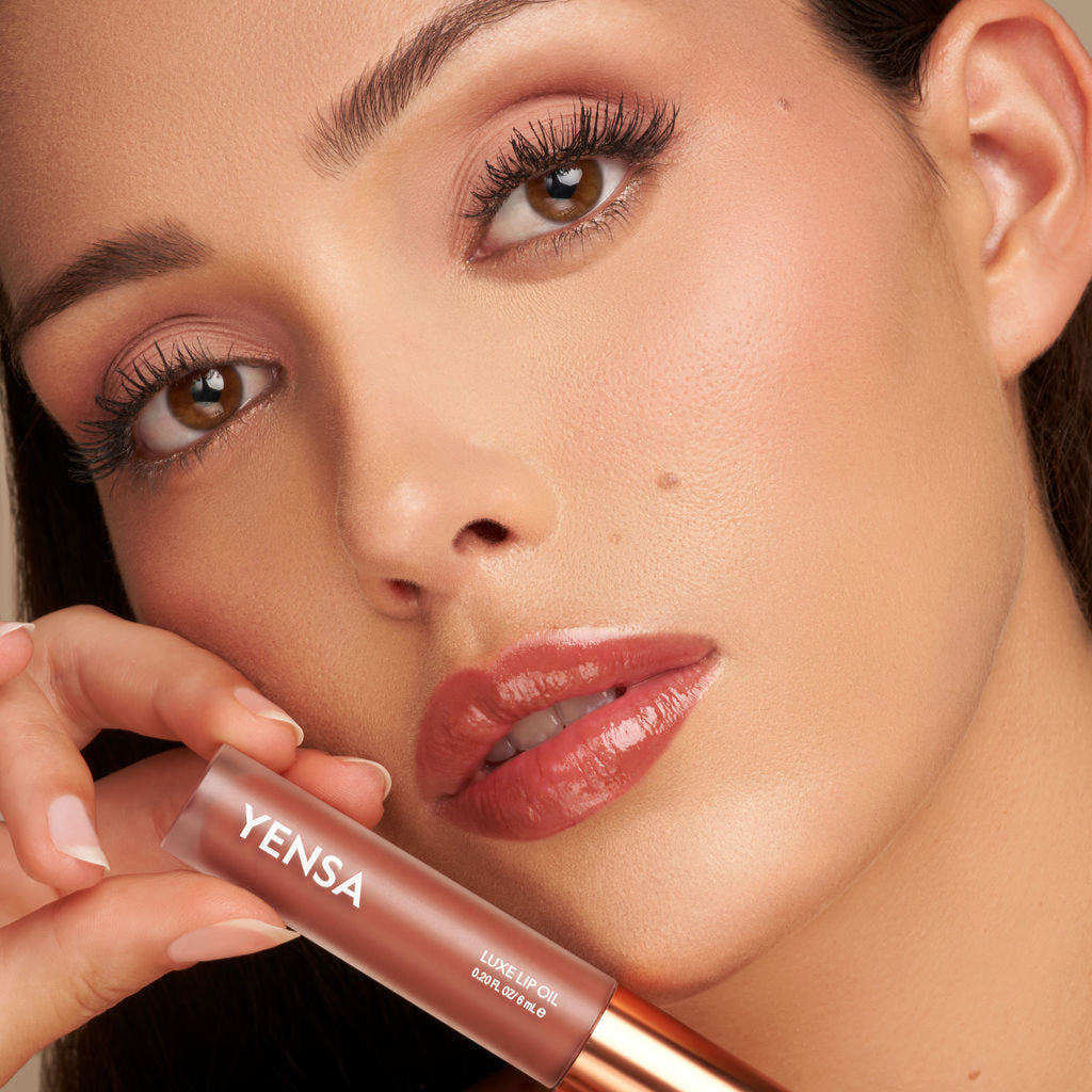 Glossy lip oil on lips with applicator held near the mouth