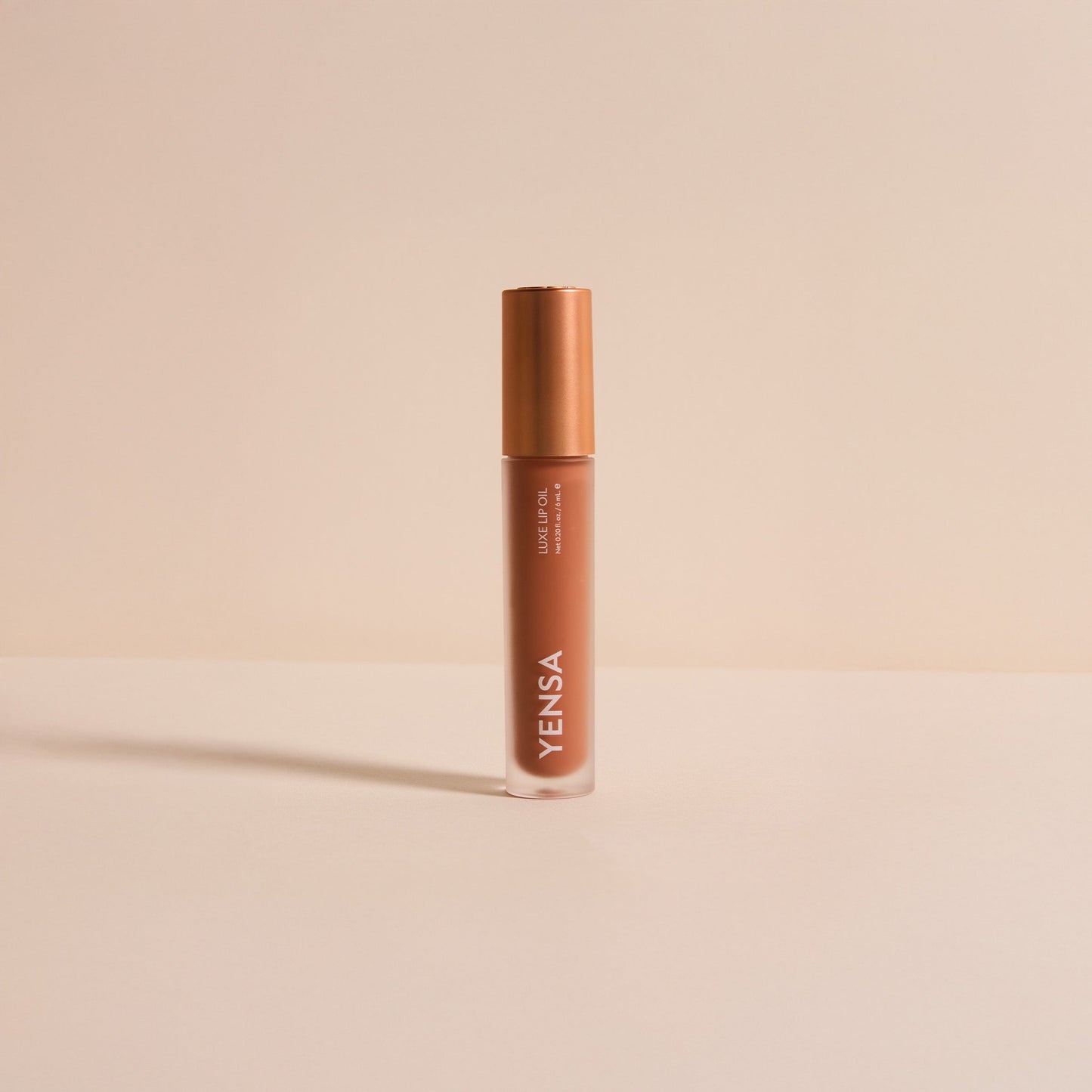 YENSA lip oil bottle with rose-gold cap, warm brown tinted gel
