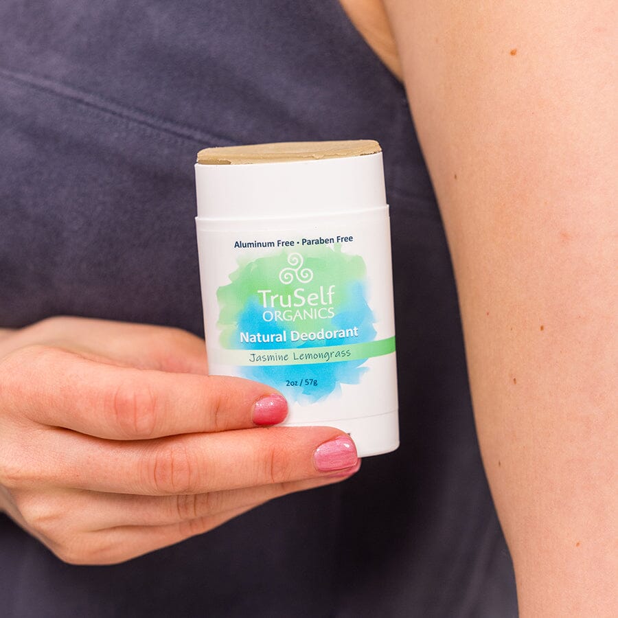 Deodorant stick, held in hand, white case with Jasmine Lemongrass label.