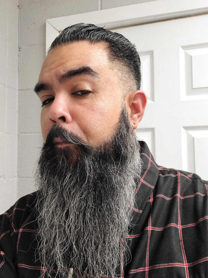 Beard oil applied to a man’s full beard with thick, dark facial hair; bottle not visible