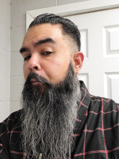 Beard oil applied to a man’s full beard with thick, dark facial hair; bottle not visible