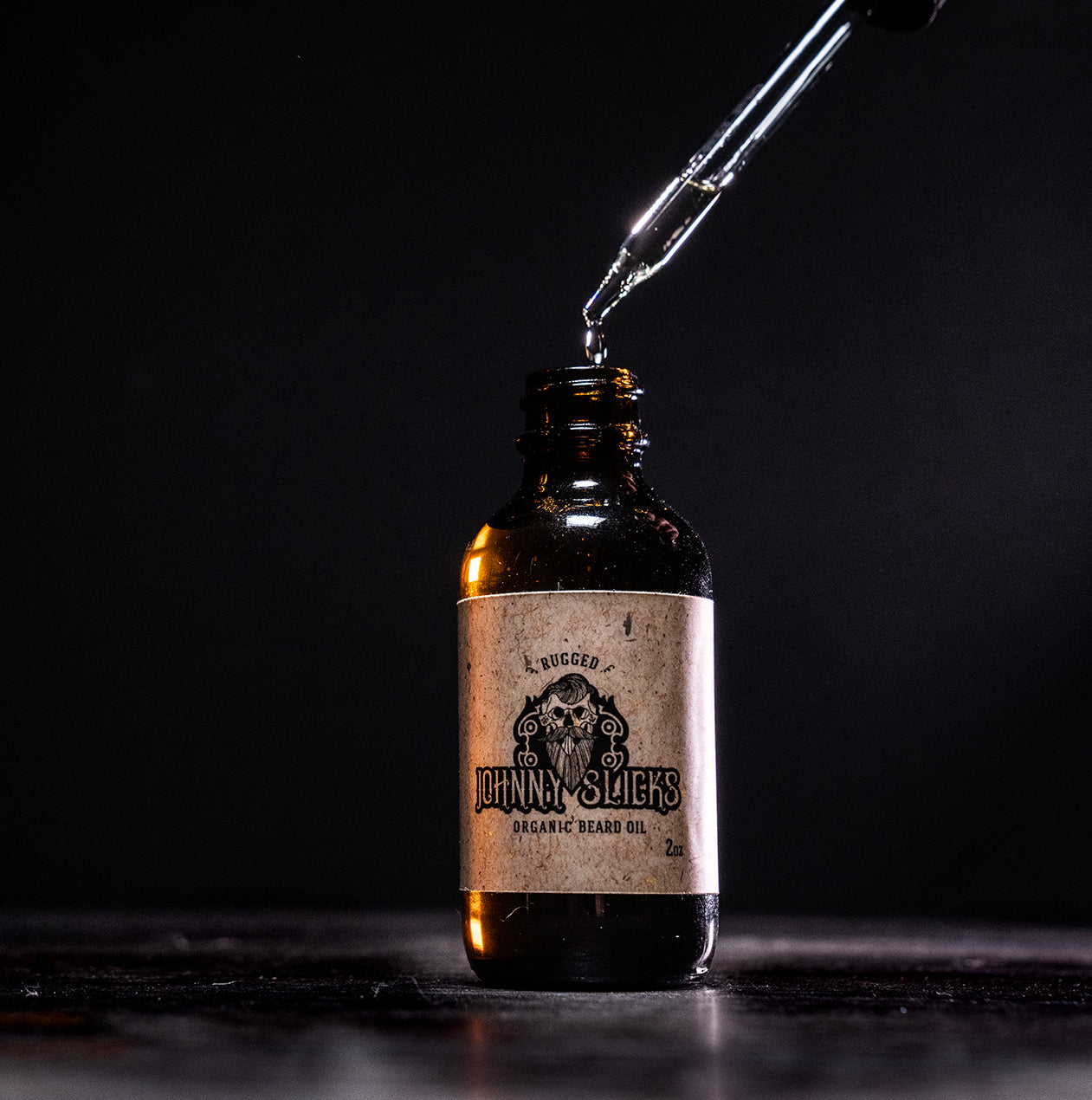 Johnny Slicks organic beard oil bottle with drop dispensing from black nozzle, amber glass