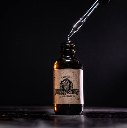 Johnny Slicks organic beard oil bottle with drop dispensing from black nozzle, amber glass
