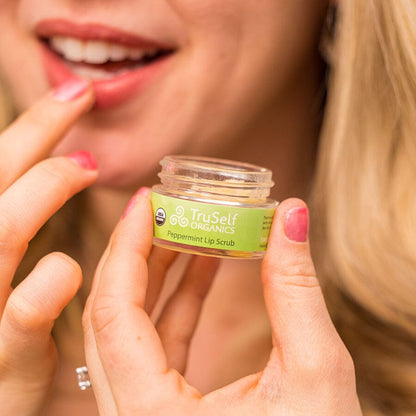 Lip scrub application: hands hold a TruSelf ORGANICS peppermint lip scrub jar.