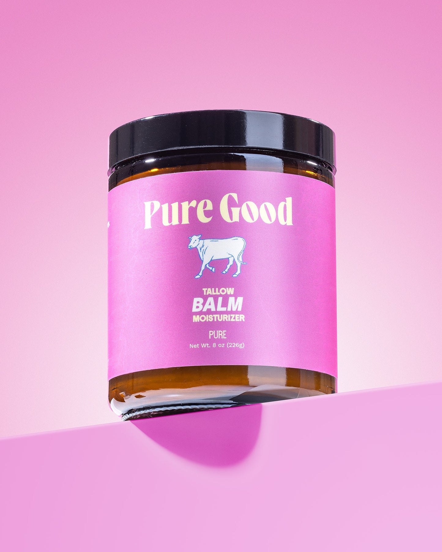 Tallow balm jar close-up, pink label with goat icon, black lid