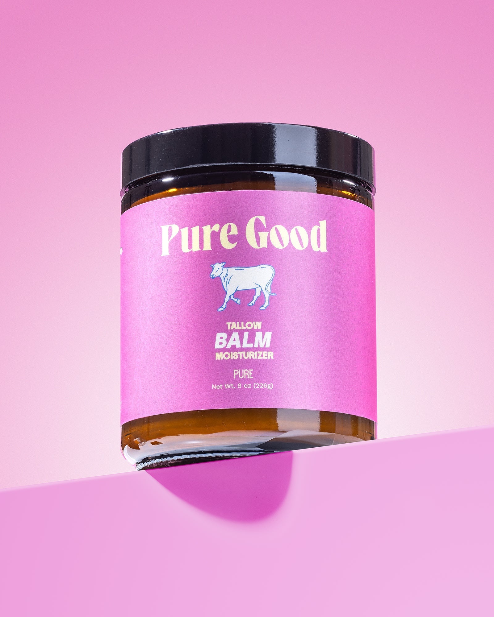 Tallow balm jar close-up, pink label with goat icon, black lid