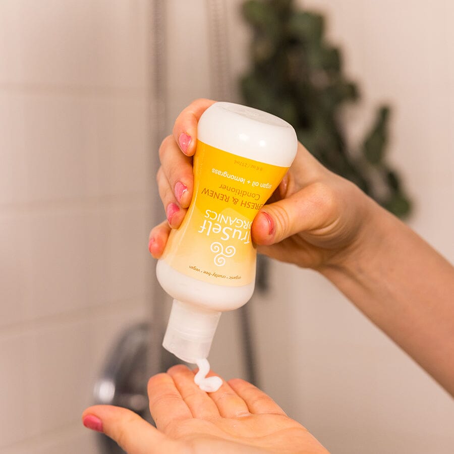 Refresh & Renew Conditioner bottle in hand with cream body and yellow TruSelf ORGANICS label
