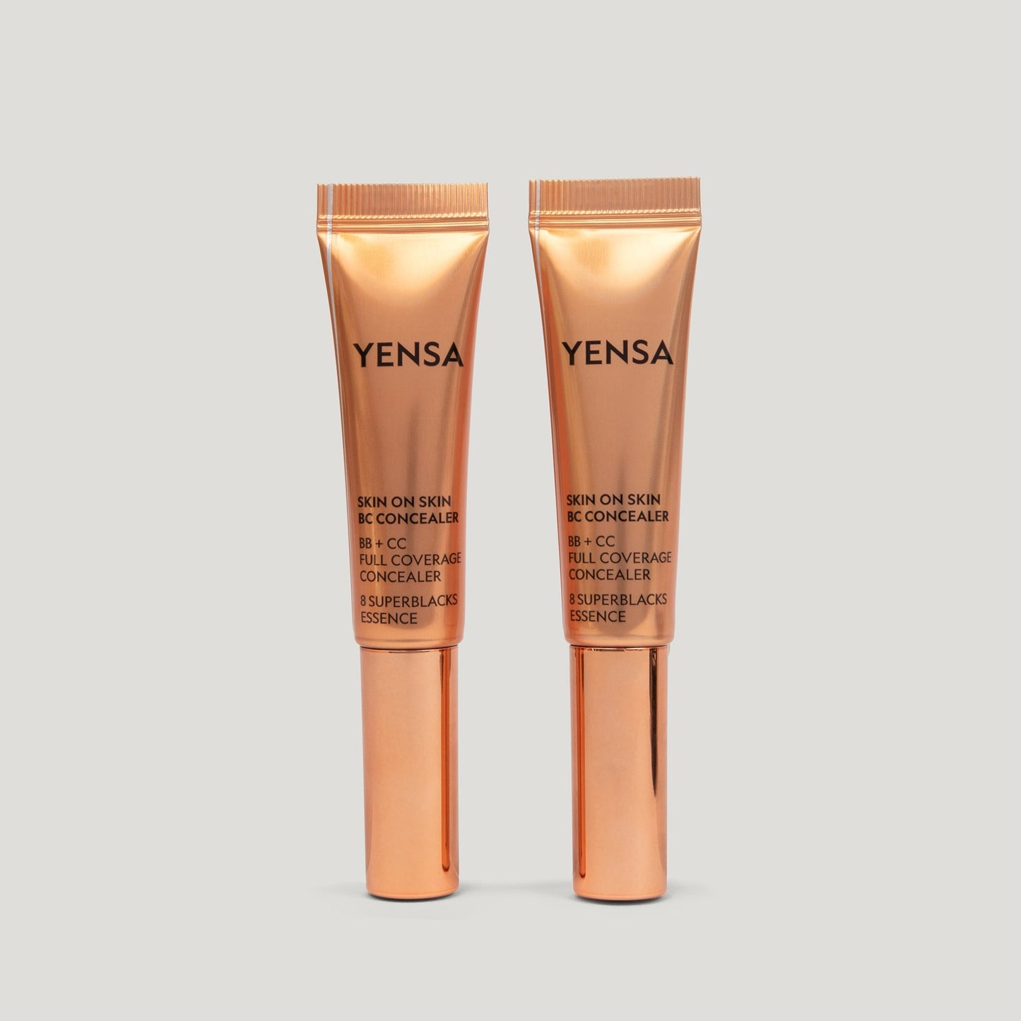 Skin concealer tube set with wand applicator, shown side by side in rose-gold packaging