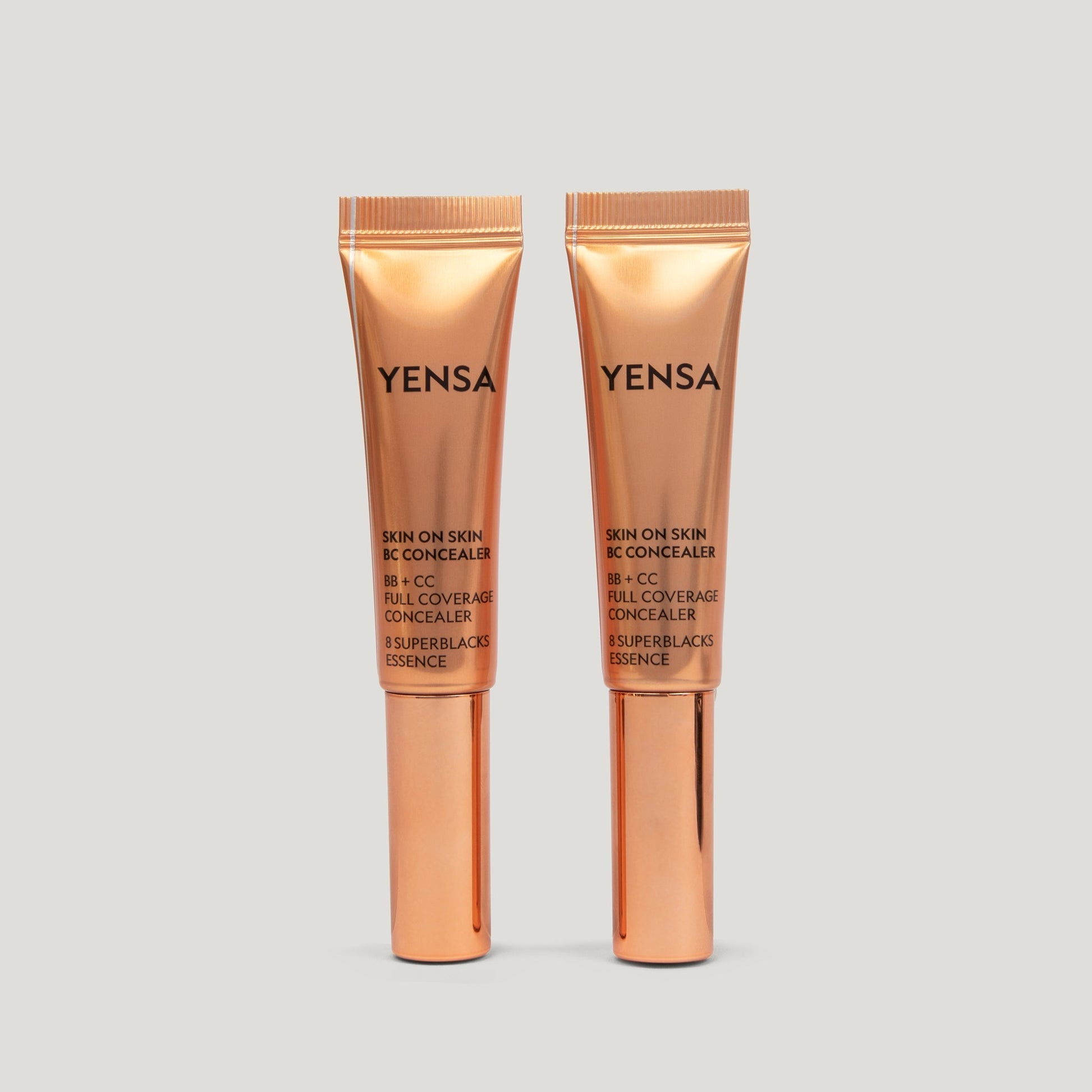 Skin concealer tube set with wand applicator, shown side by side in rose-gold packaging