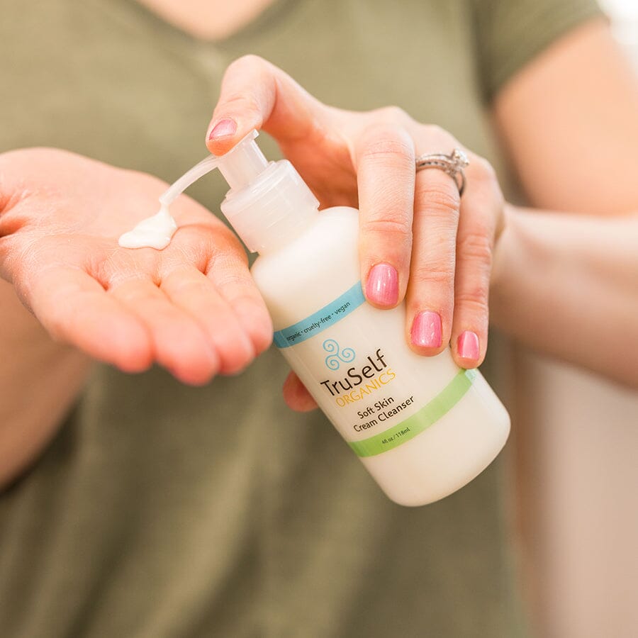 Cream cleanser pump bottle in hands, white bottle with green label strip