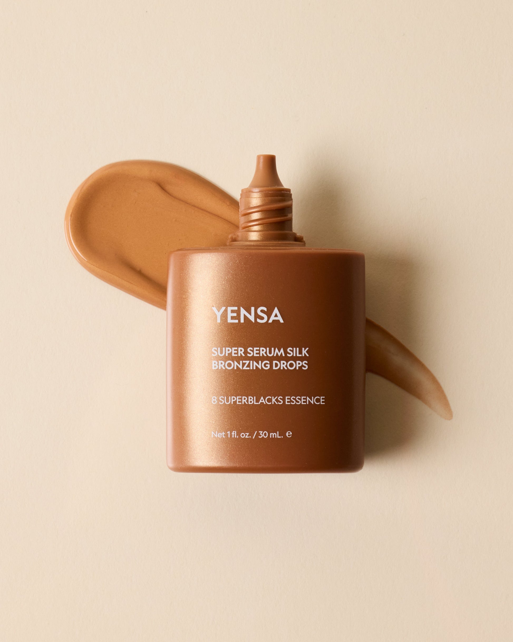 Bronzing drops bottle with bronze serum smear behind, smooth golden-brown gel