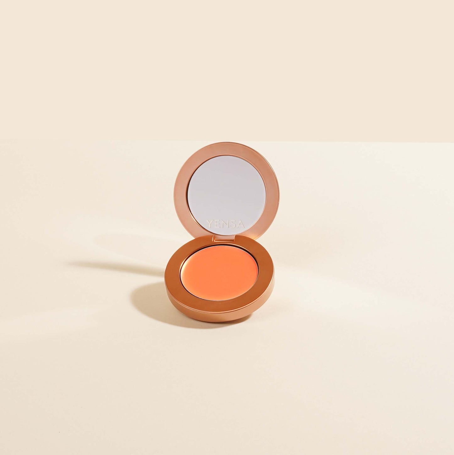 Cream blush compact with open lid showing a peachy orange shade in the pan.