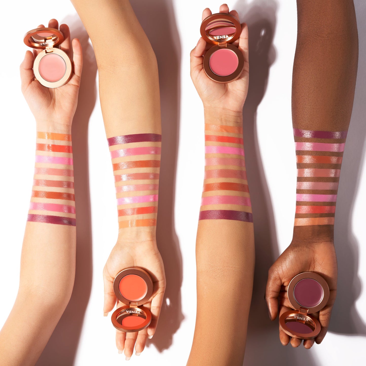 Cream blush applicaton on arms, holding compacts with visible striped swatches.