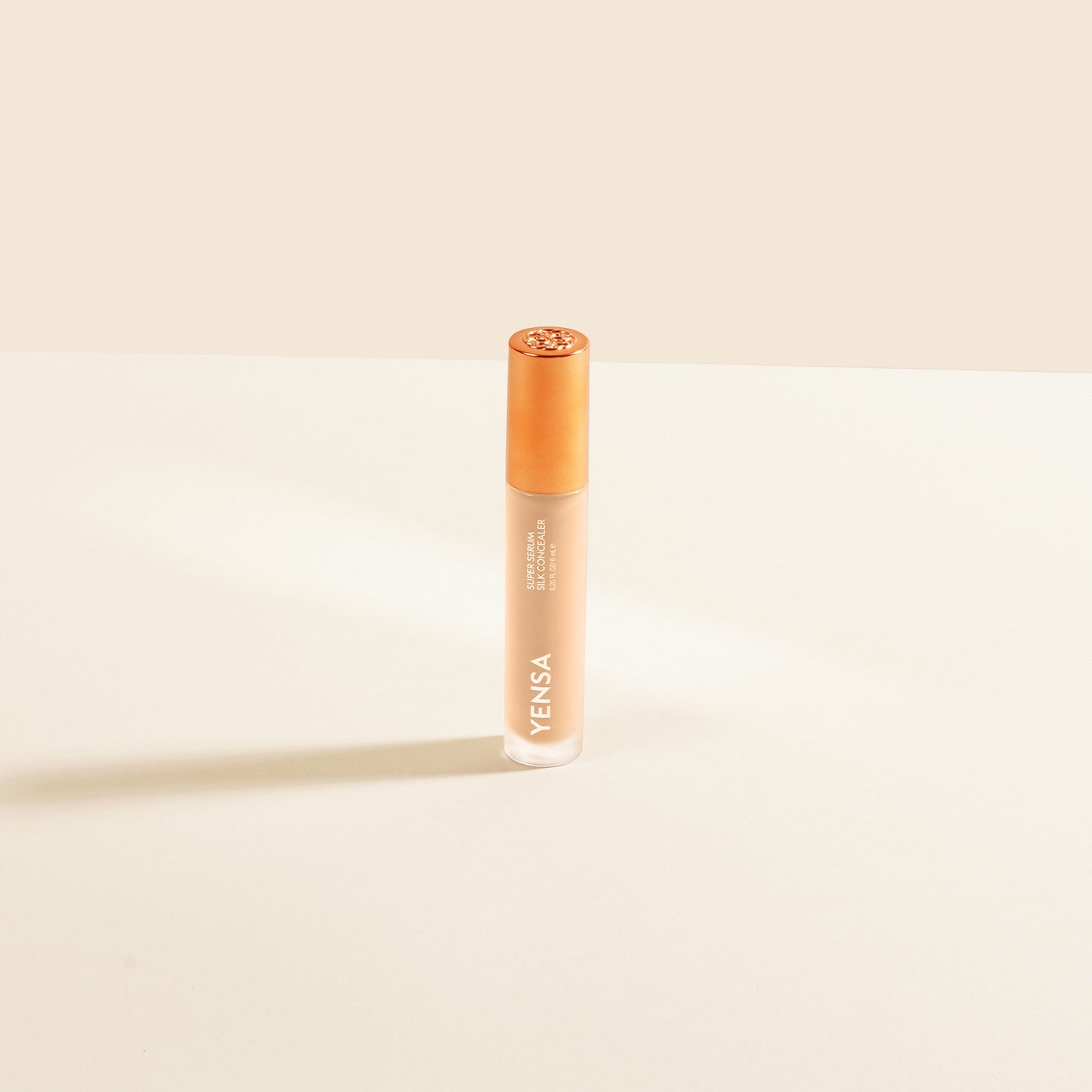Silk concealer serum bottle with copper cap and warm beige liquid
