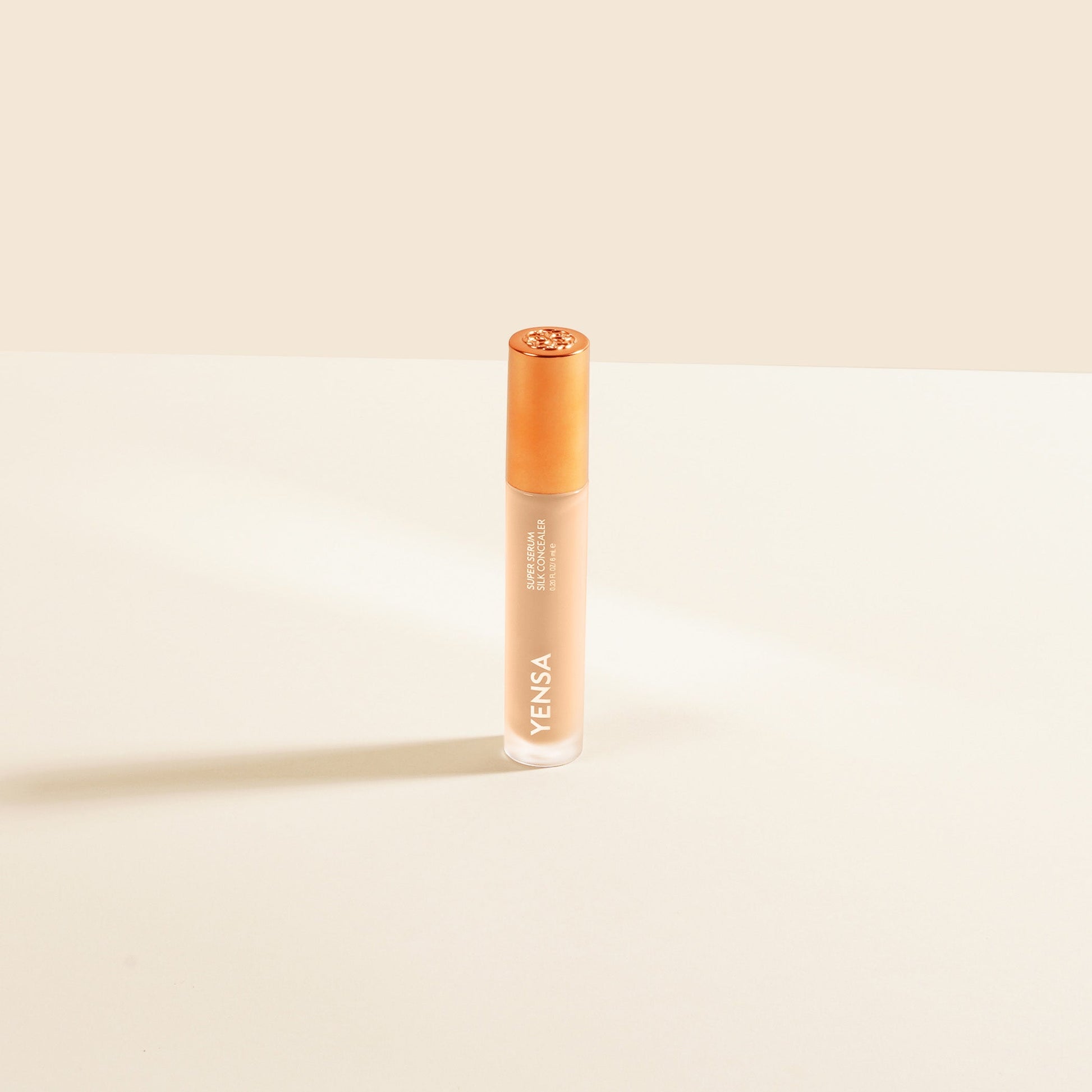 Silk concealer serum bottle with copper cap and warm beige liquid