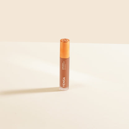 Concealer tube standing upright, light peach liquid with rose-gold cap