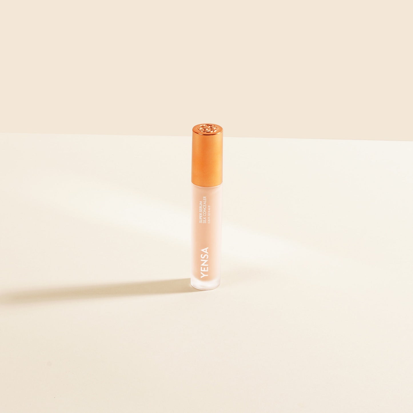 Silk serum concealer bottle with rose-pink liquid and gold cap, upright