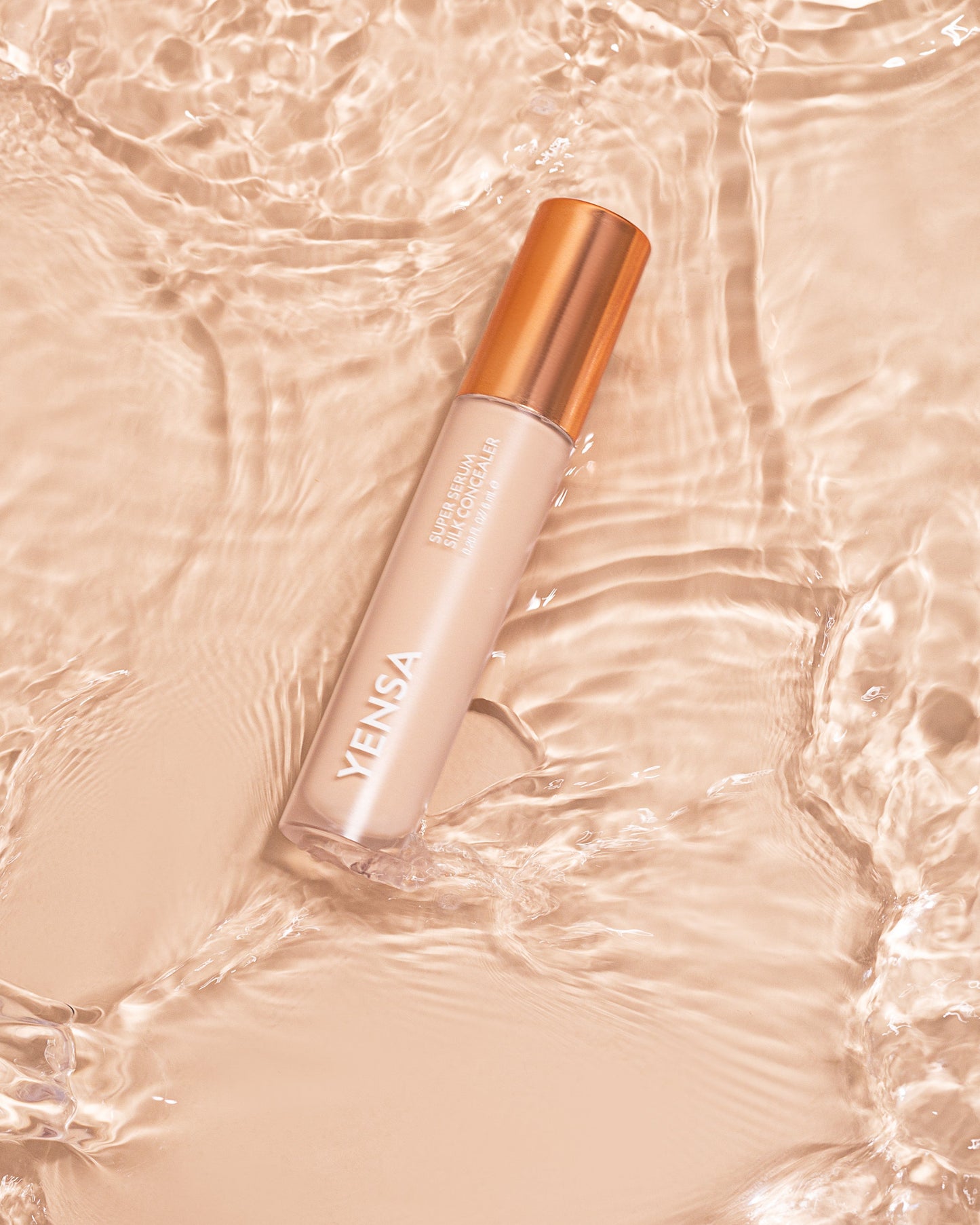 Silk serum concealer bottle with rose-gold cap and light beige tint, angled