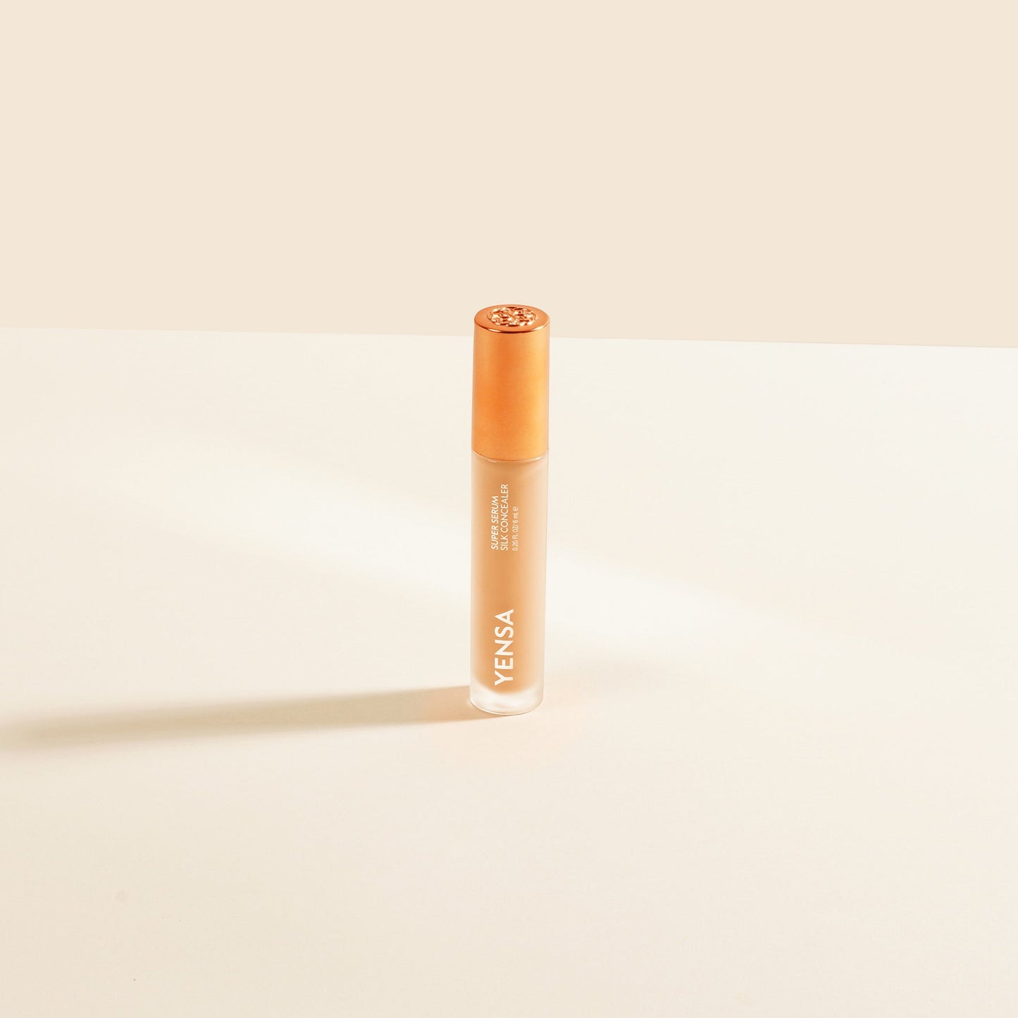 Concealer tube with rose-gold cap, light peach liquid shade