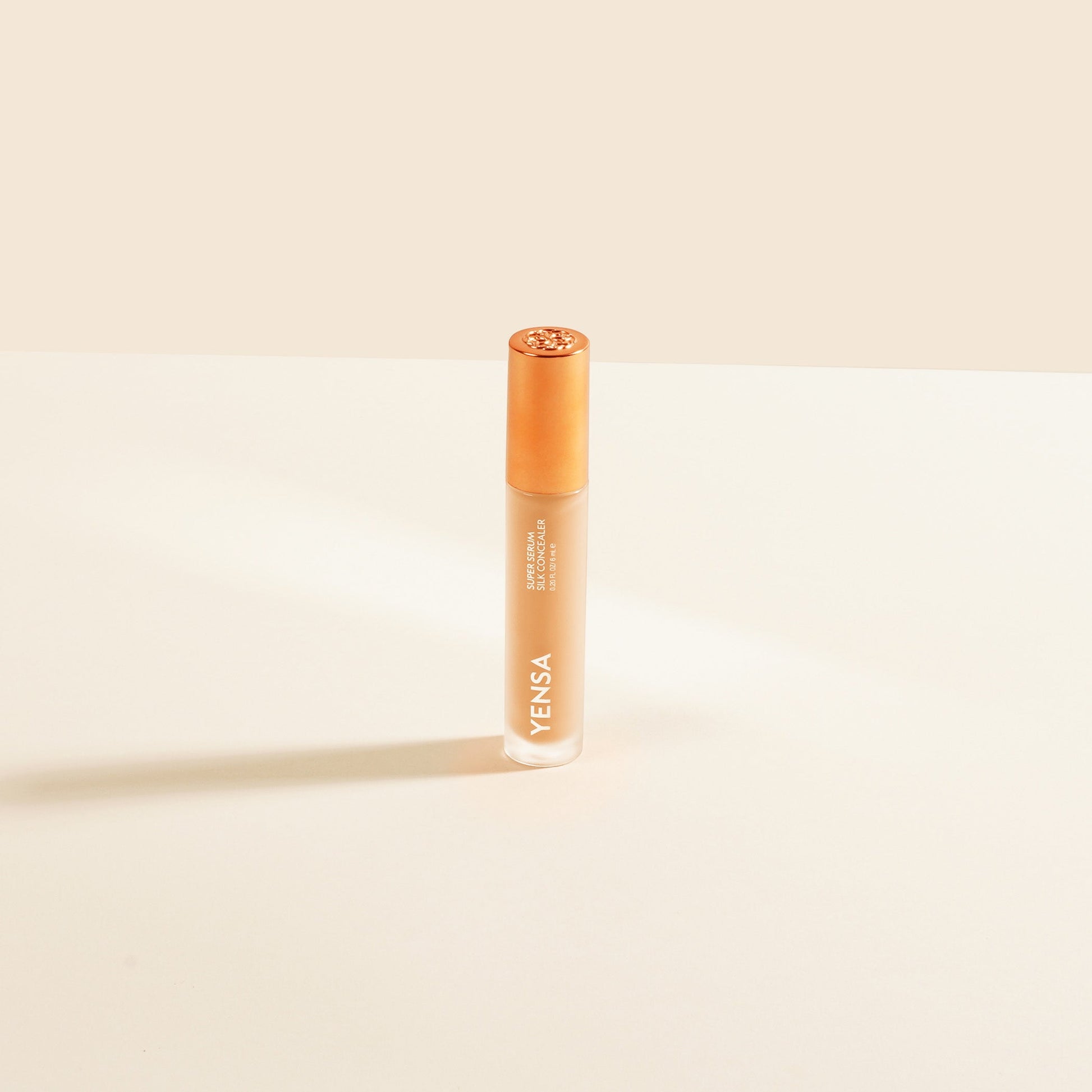Concealer tube with rose-gold cap, light peach liquid shade