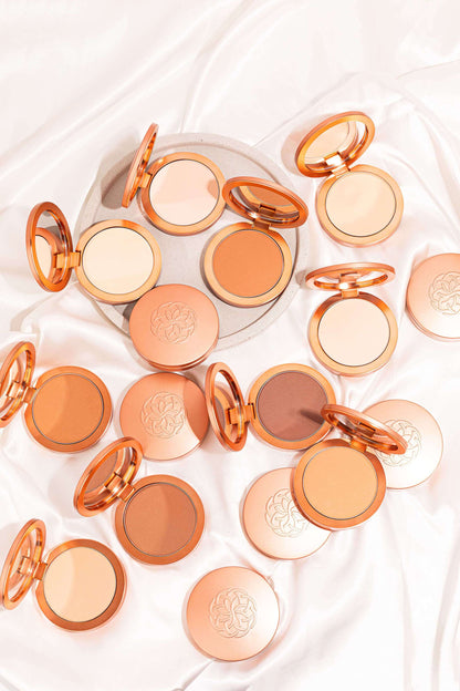 Powder foundation compact collection in orange-gold cases, open pans showing matte powders