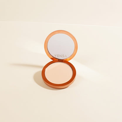Powder foundation compact with open lid, pale peach-beige matte powder disc