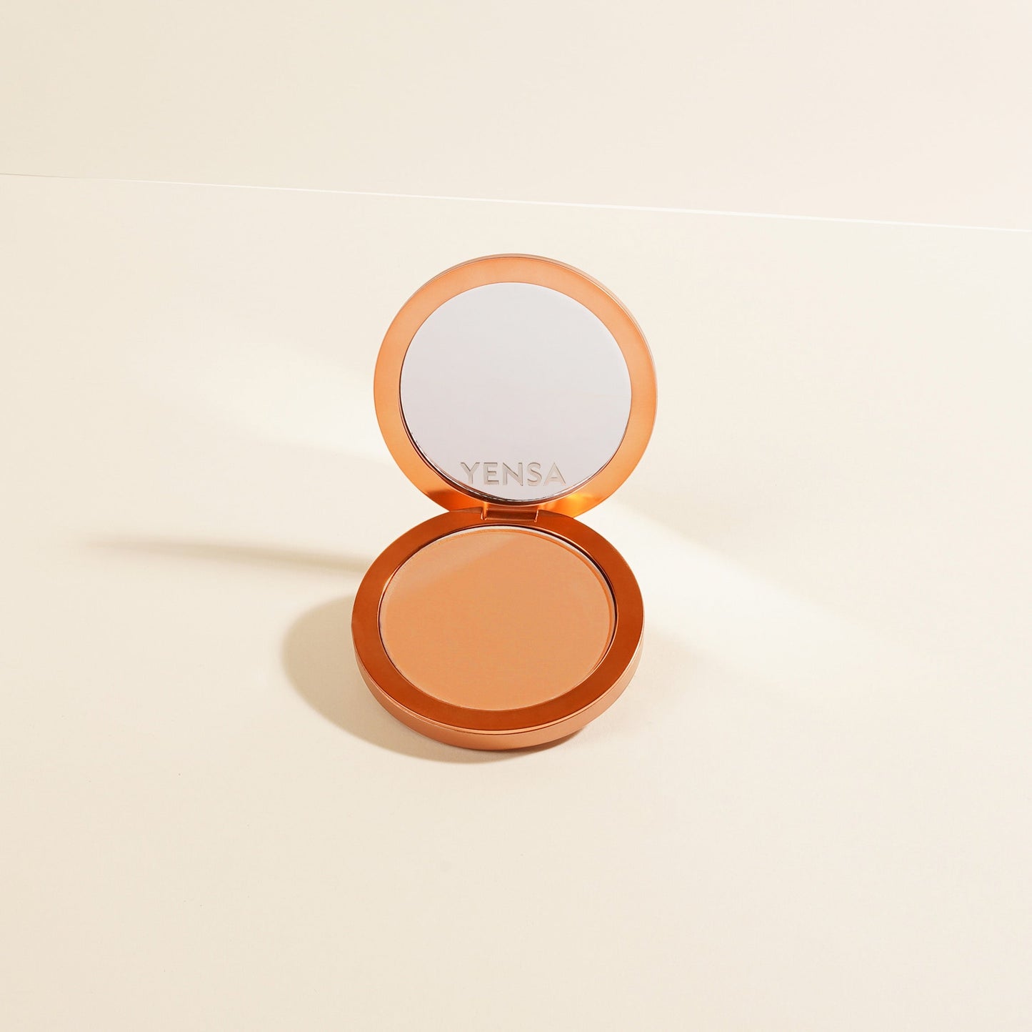 Compact powder foundation with mirror and round pan, tan-beige shade visible