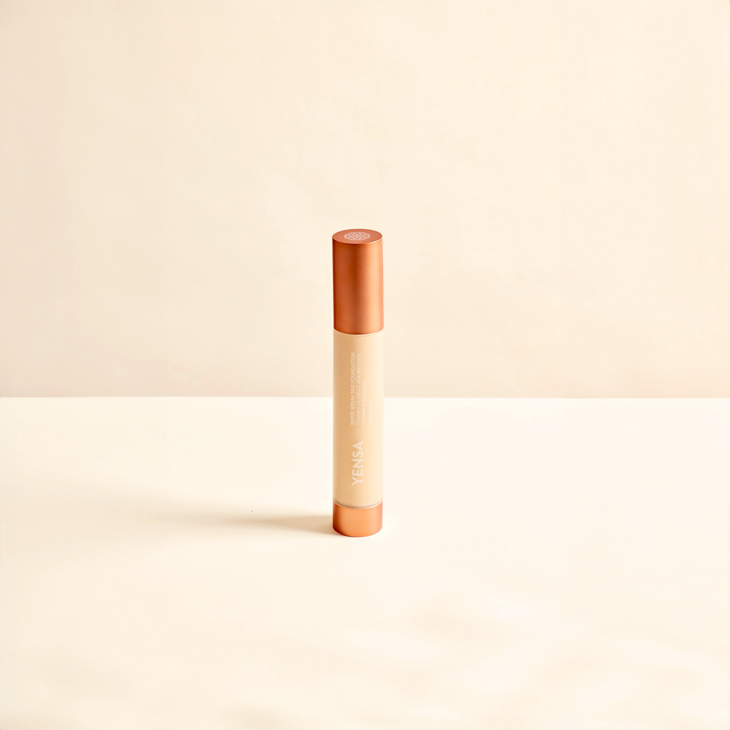 Foundation tube with coral top and light cream liquid, shown upright.