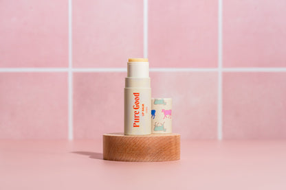 Tallow lip balm in cream and pastel purple tubes on a round wooden base