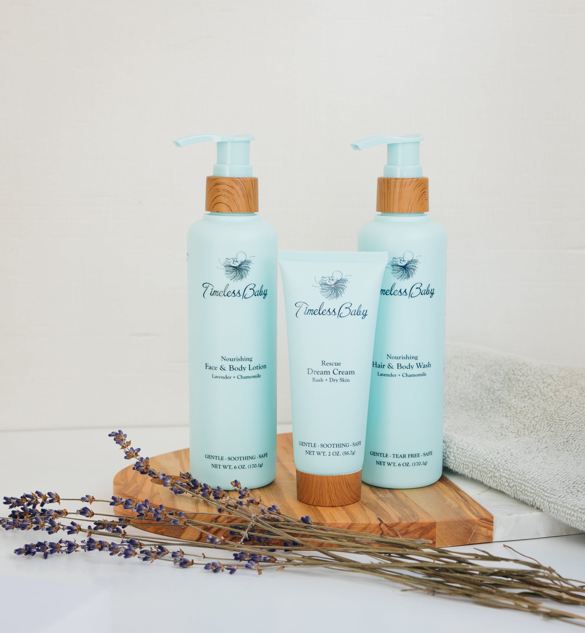 Baby skincare set with two light blue pump bottles and a cream tube, bamboo caps