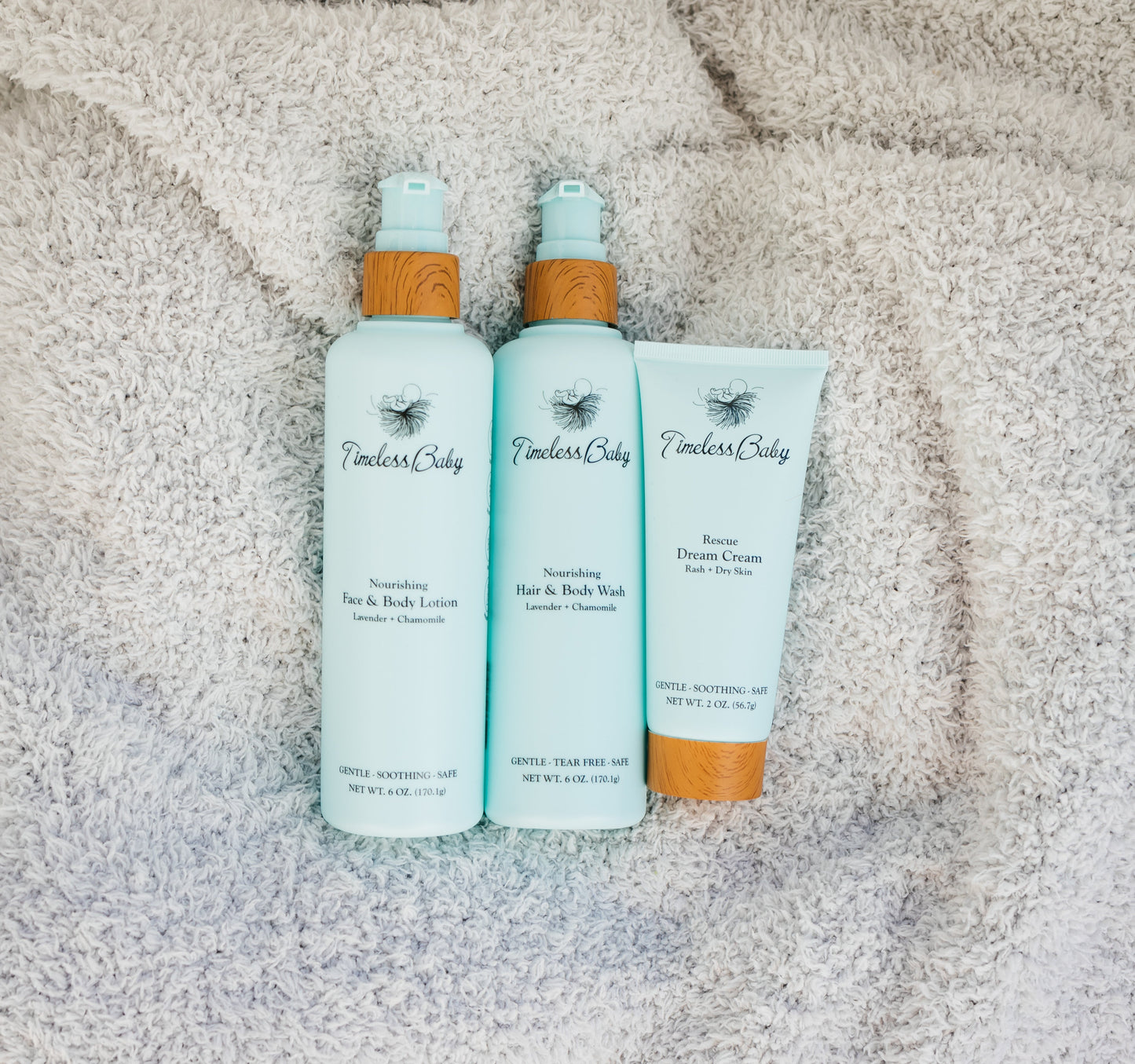 Baby skincare set: two light blue pump bottles and a cream tube with bamboo caps