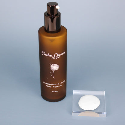 Clarifying acne lotion bottle with black pump and white product sample in tray