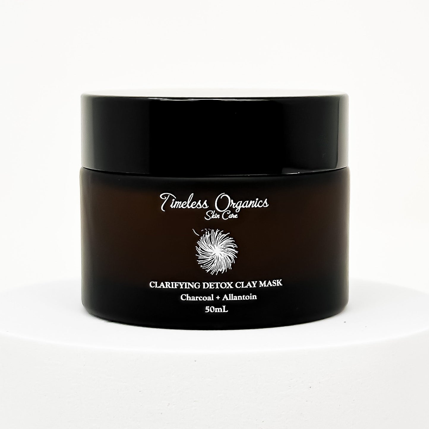 Black clay face mask jar with gold label text and flip-top lid