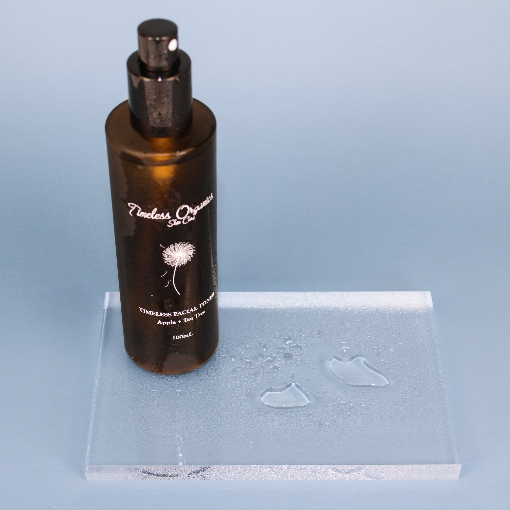 Clarifying facial toner bottle with black pump and amber glass with water droplets